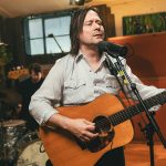 Les Thomas holding a guitar